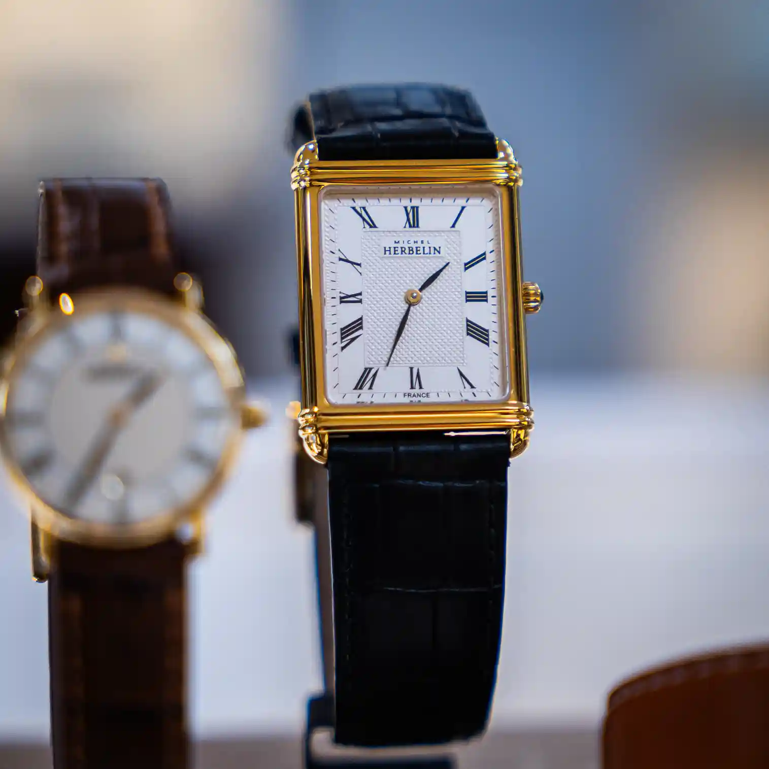 Een rechthoekig Michel Herbelin horloge antares collectie met leren band staat rechtop in de vitrine