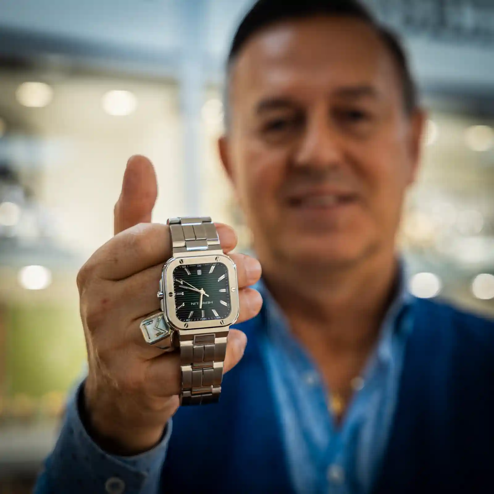 Een medewerker houdt een stalen Michel Herbelin horloge voor de camera in de juwelierswinkel