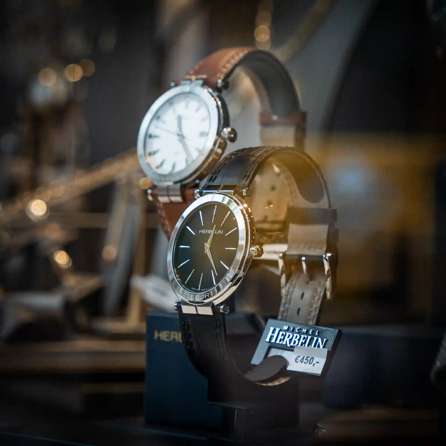 In de vitrine staan twee Michel Herbelin horloges voor heren met leren horlogebanden