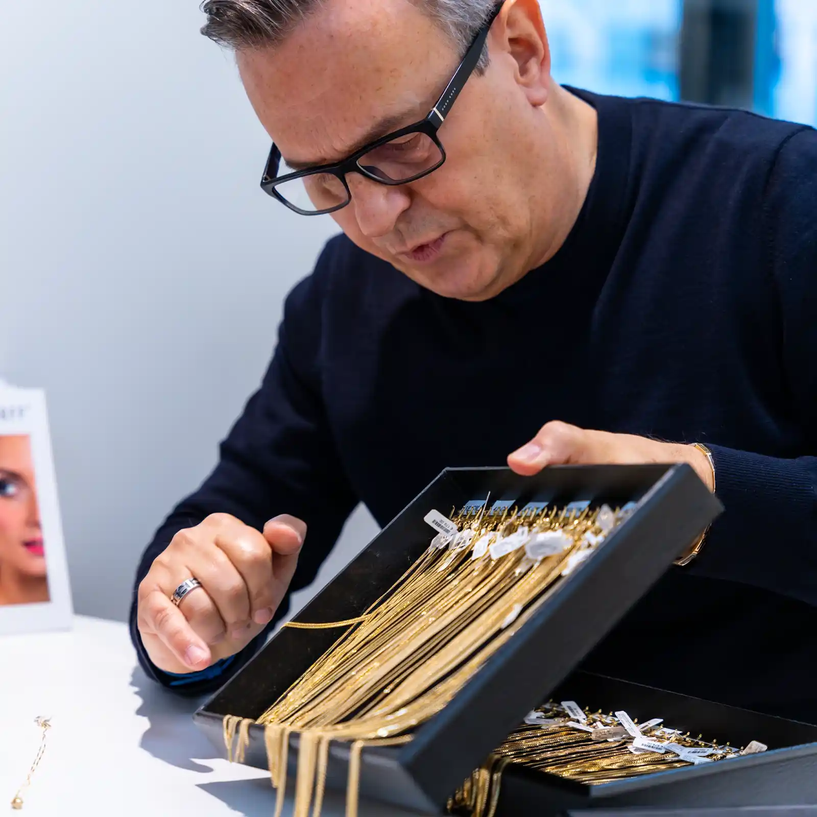 Rij fijne gouden colliers klaarliggend om uit te kiezen bij juwelier in stadswinkel