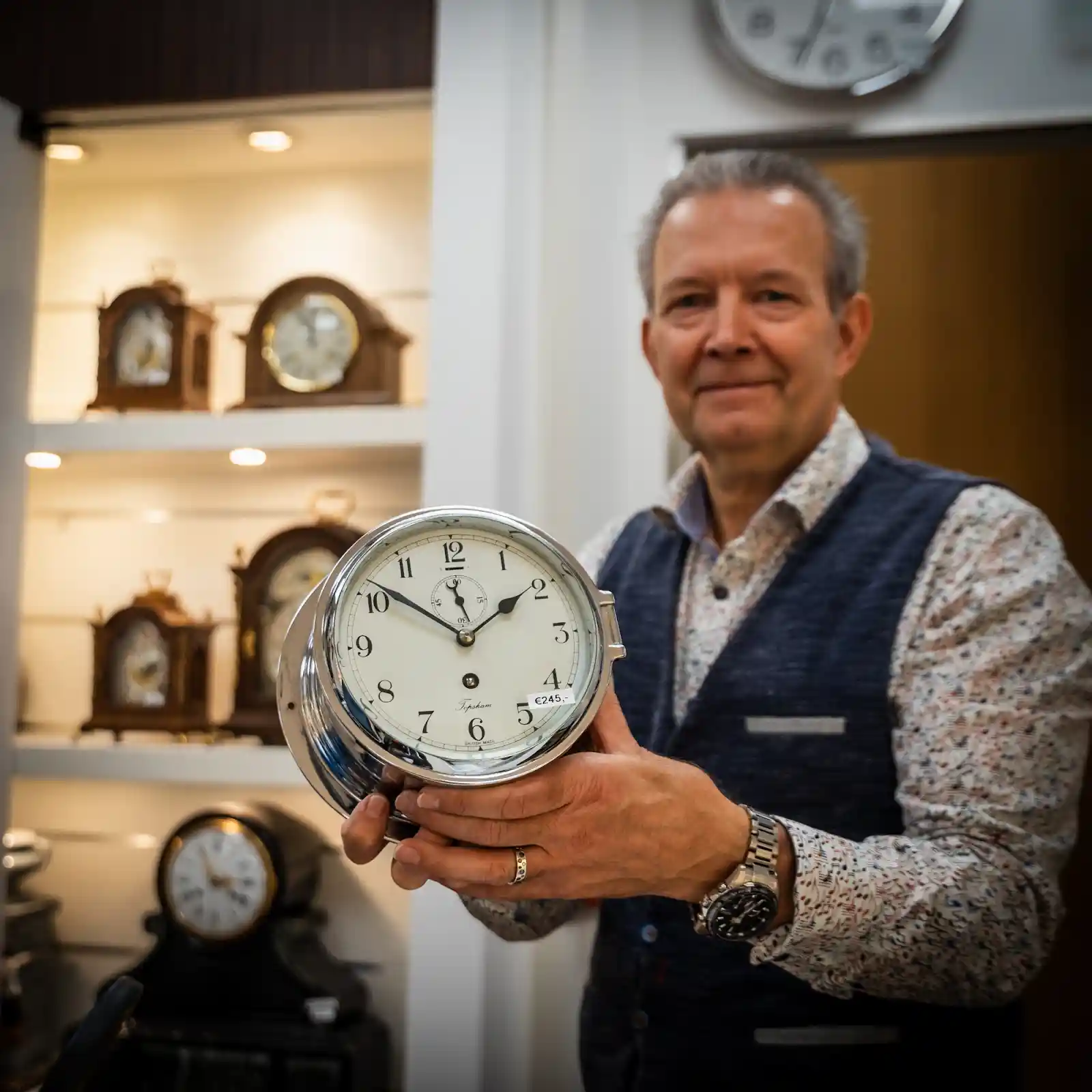 Medewerker toont een modern wandklok in de klokkenwinkel